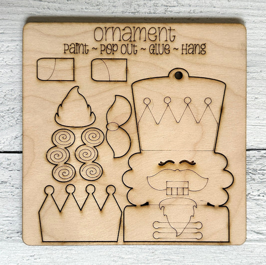 Wooden cutout with laser-engraved nutcracker design elements for a Christmas ornament on a light wooden surface.